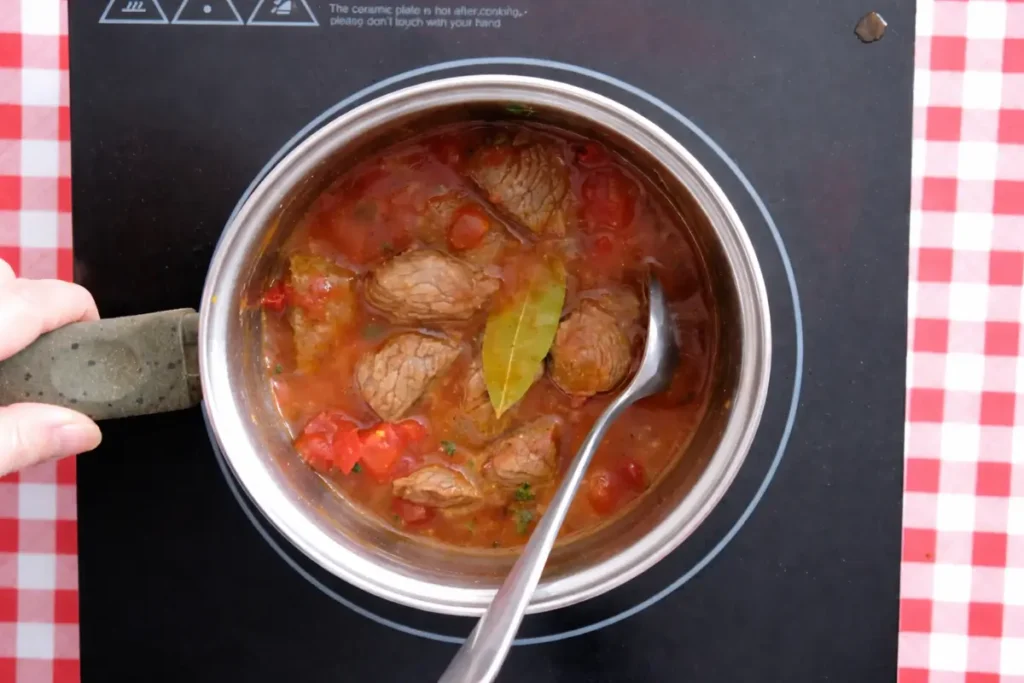 Beef simmering with tomatoes and bay leaf in a rich broth.