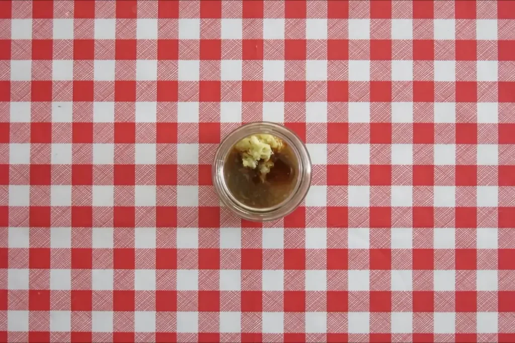Lemon and ginger dressing in a small glass jar before shaking.