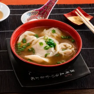 Bowl of Low FODMAP wonton soup topped with sliced green onion in a red serving bowl.