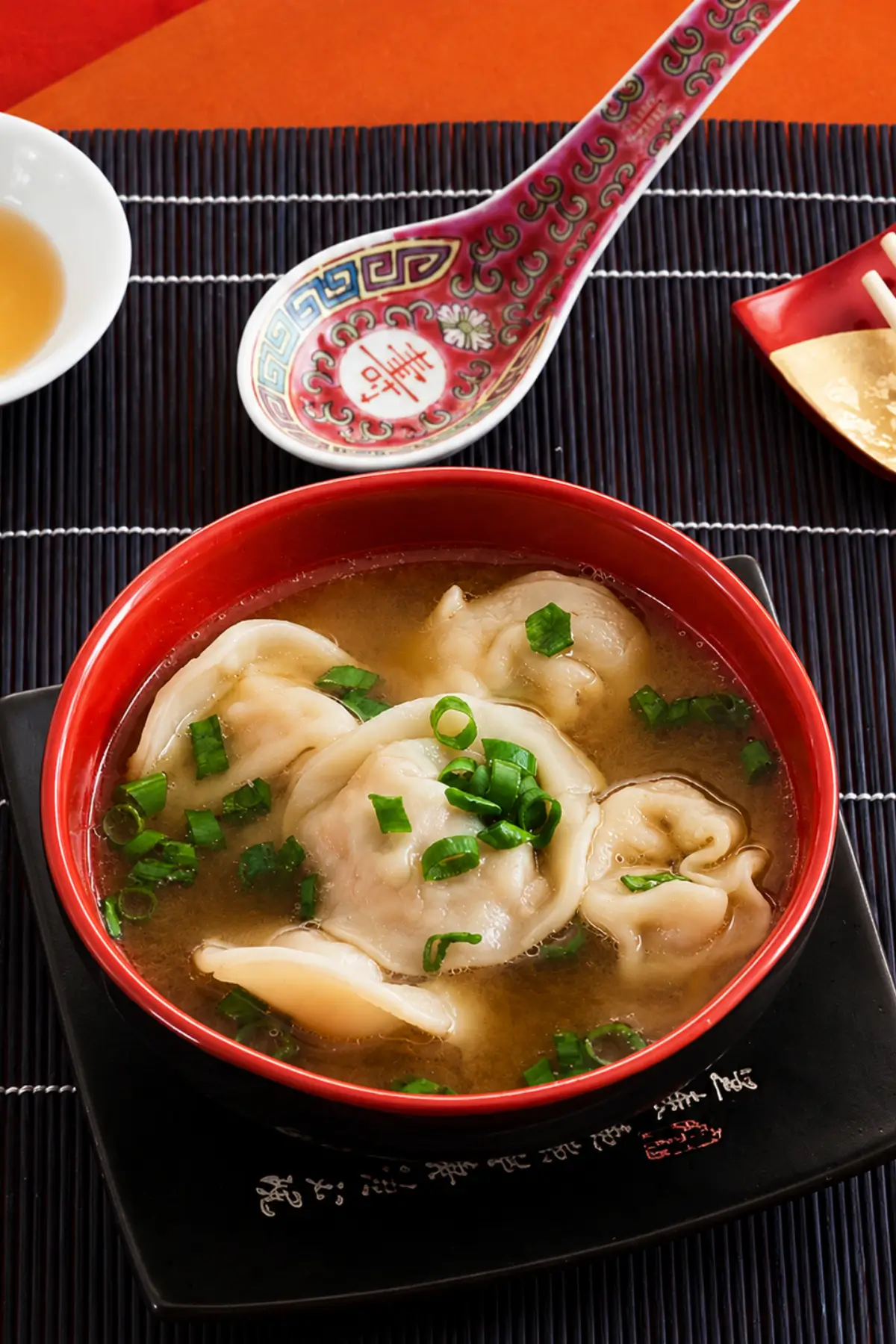 Soft pork wontons served in a light savoury broth with green onion tops.