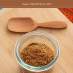Low FODMAP Taco Seasoning stored in a small glass jar on a wooden board.