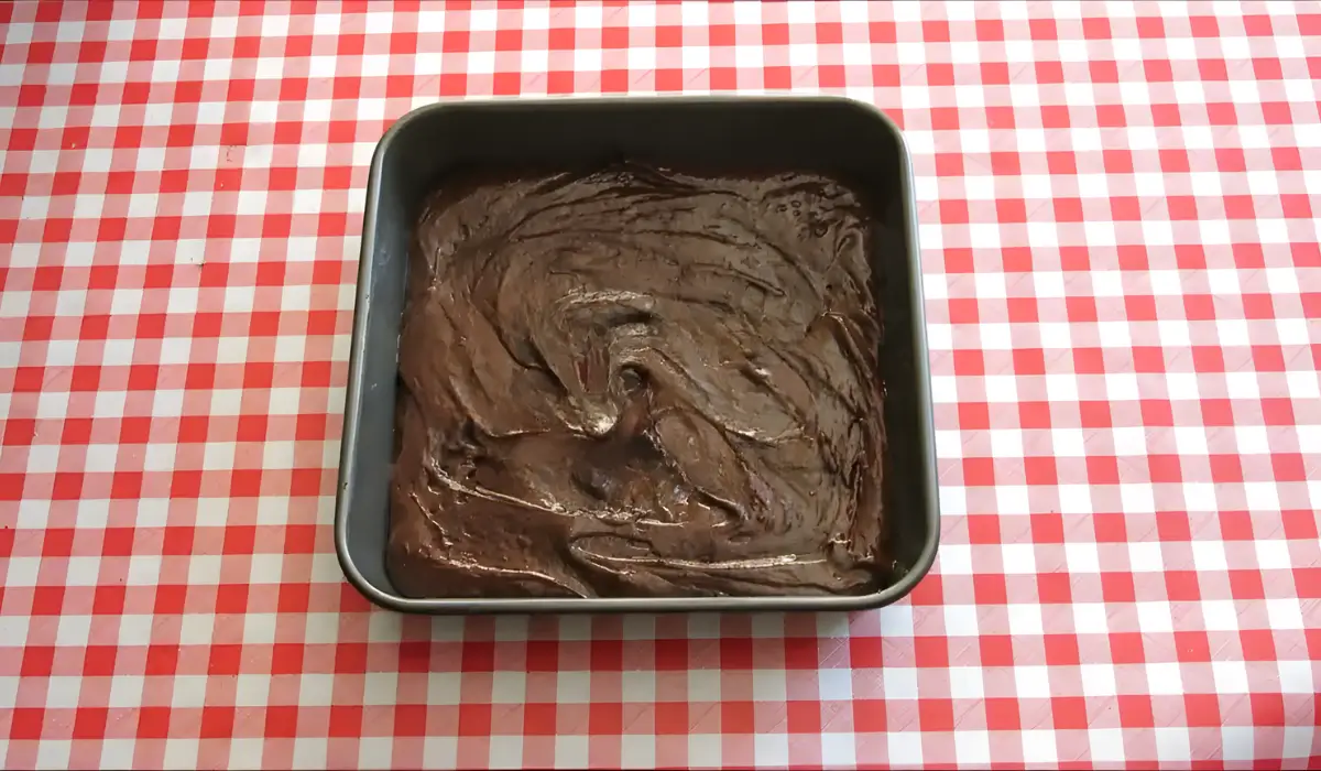 Brownie batter spread evenly in square baking tin.