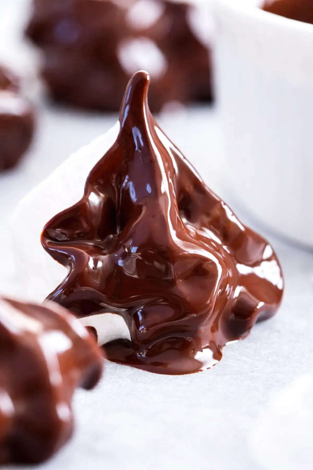 Detailed view of melted chocolate coating a meringue with soft folds and glossy finish.