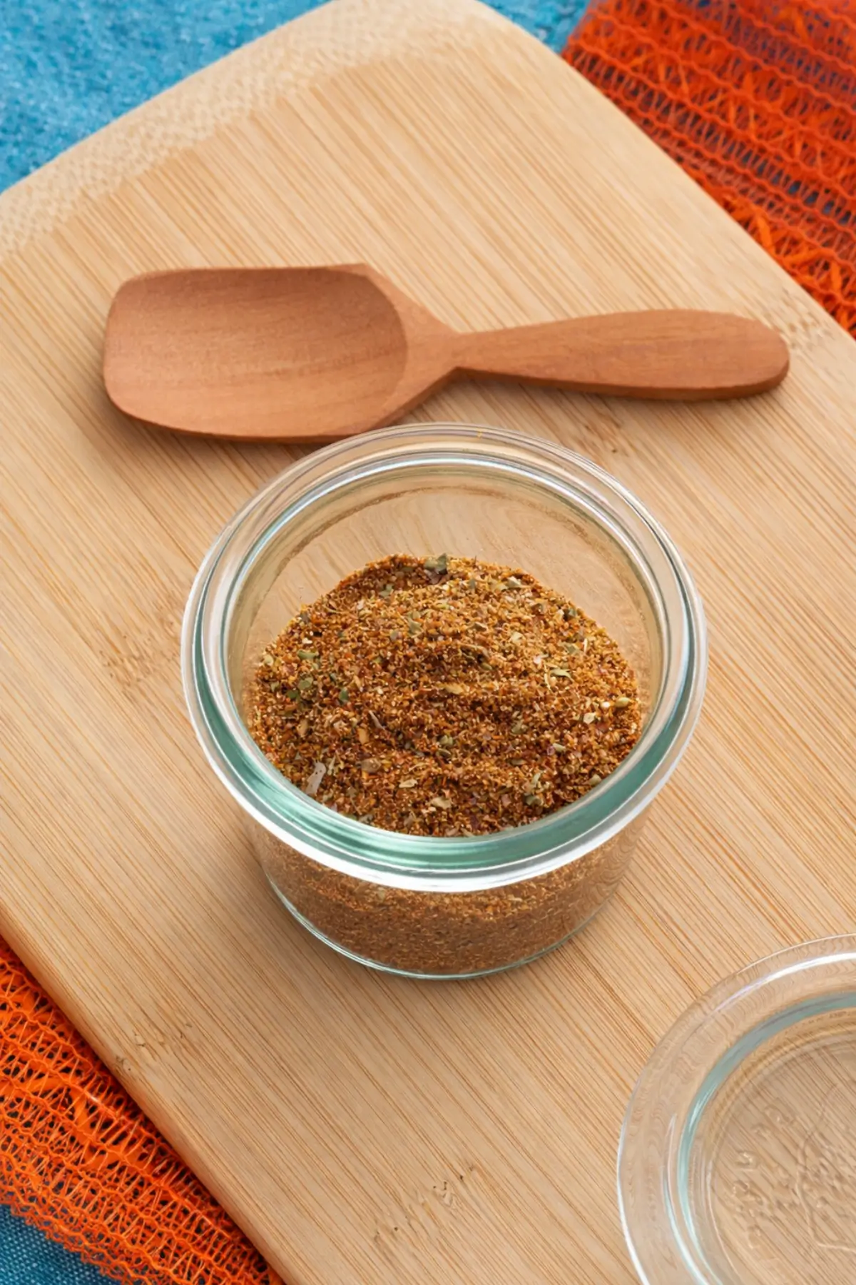 Close-up of a homemade spice blend in a clear jar on a bamboo board.