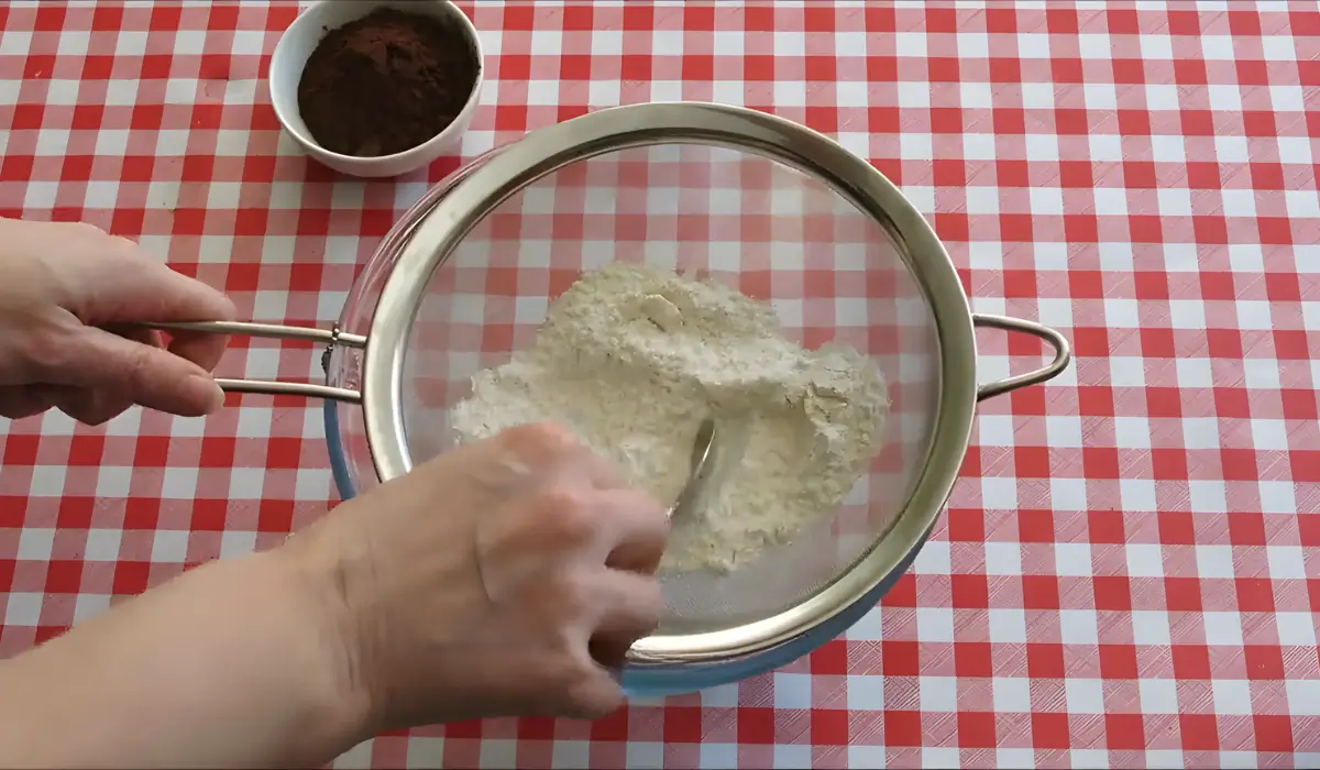 Sifting flour and cocoa powder together into bowl.