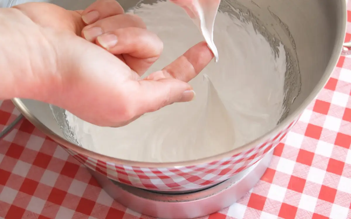 Whipped egg white mixture forming stiff peaks in a mixing bowl.