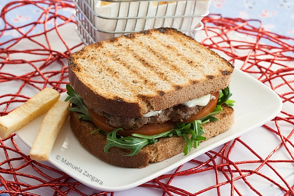 Low FODMAP Beef Burger served on toasted sourdough with rocket, tomato and fries.