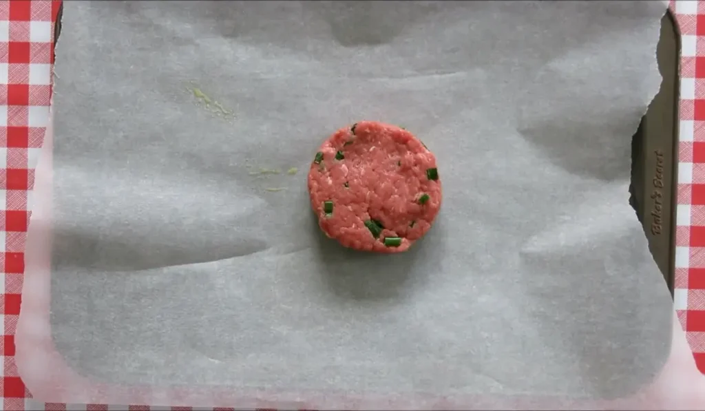 Raw beef patty shaped into a neat round on baking paper