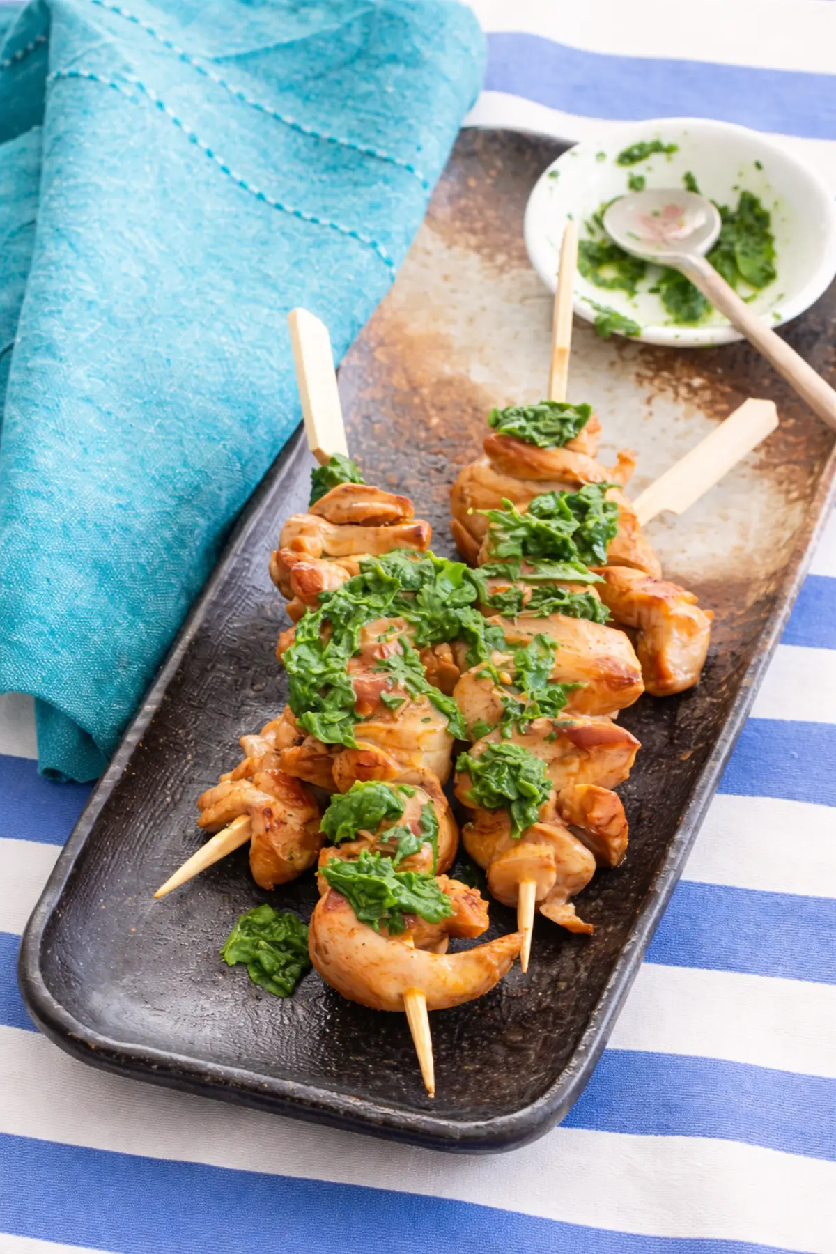 Grilled chicken skewers topped with fresh herb sauce.