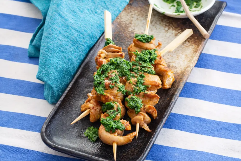 Portuguese chicken skewers finished with a spoonful of herb sauce.