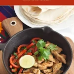 Chicken fajitas in a skillet with capsicum, lime, and coriander.