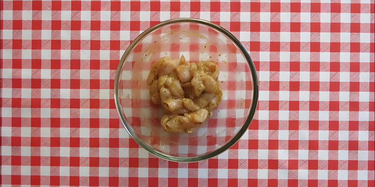 Sliced chicken coated in marinade in a glass bowl.
