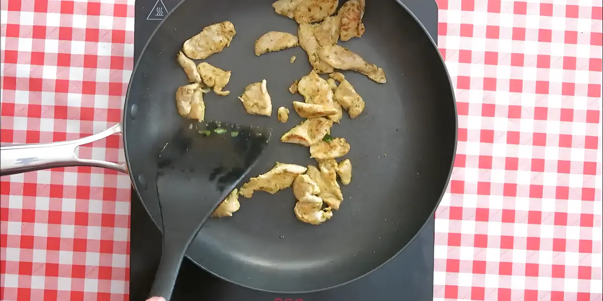 Chicken strips cooking in a non-stick pan.