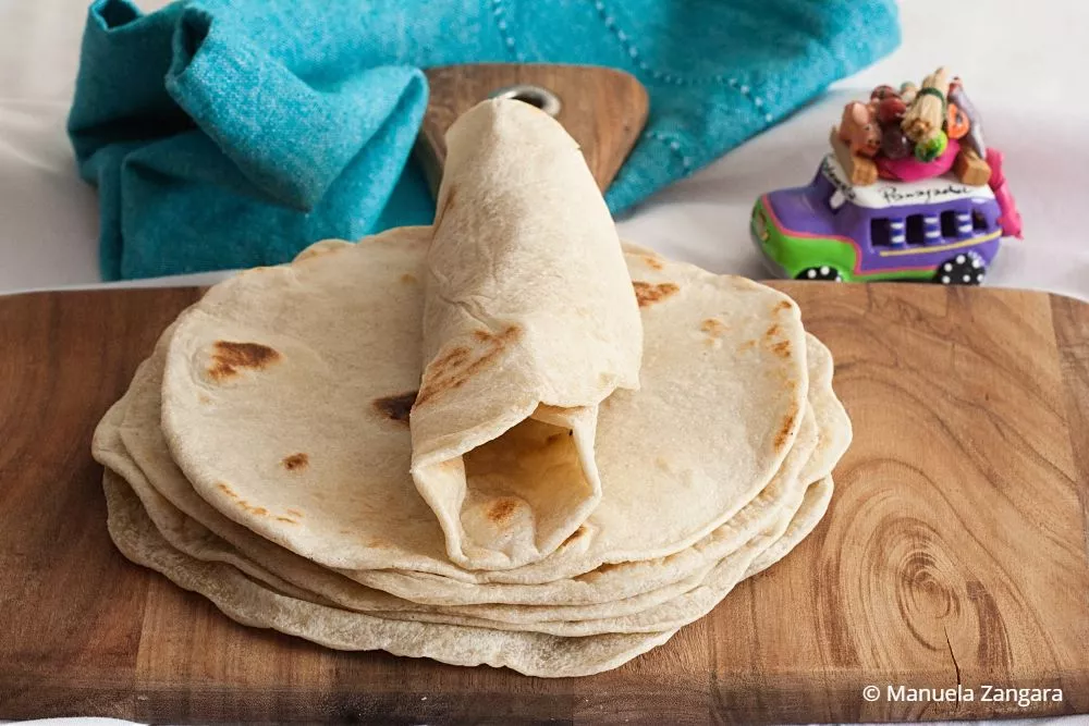 Folded low FODMAP tortilla on top of a stack with teal napkin and toy car in the background.