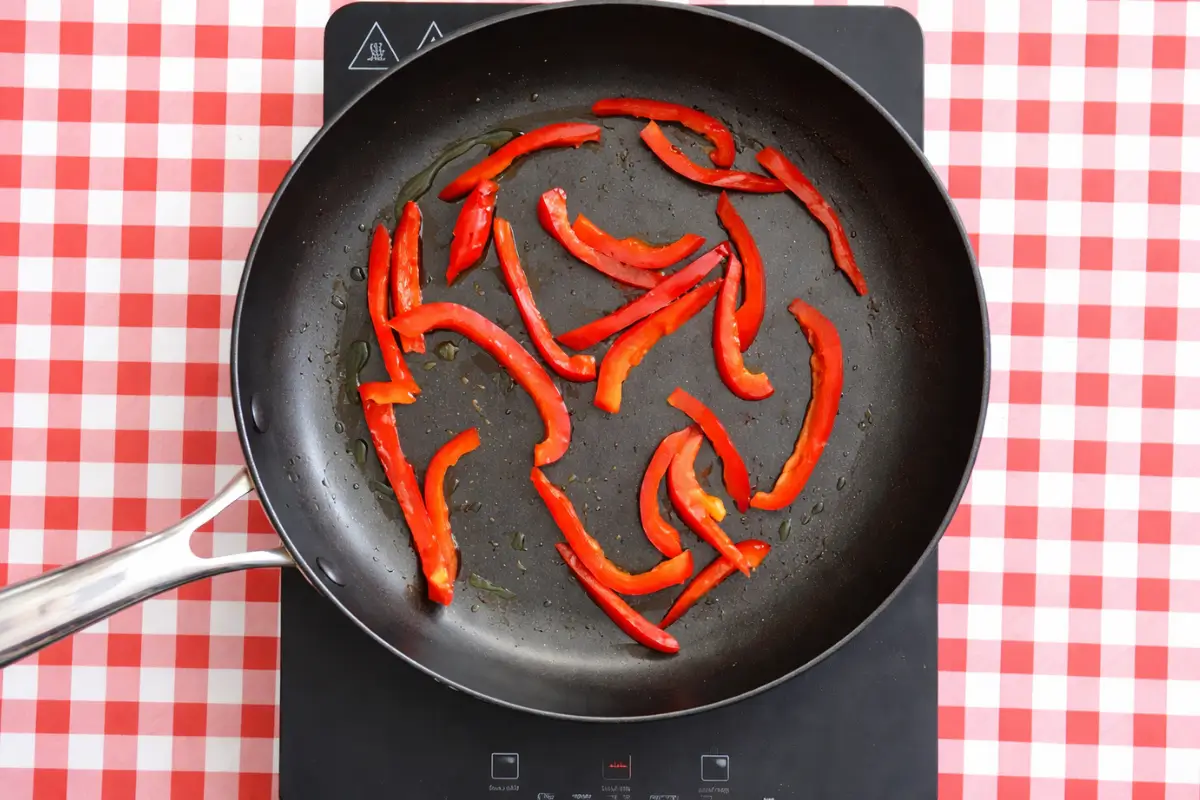 Red capsicum sautéing in oil.