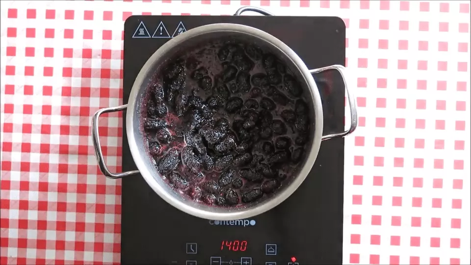 Mulberries cooking down in a pot on the stove.