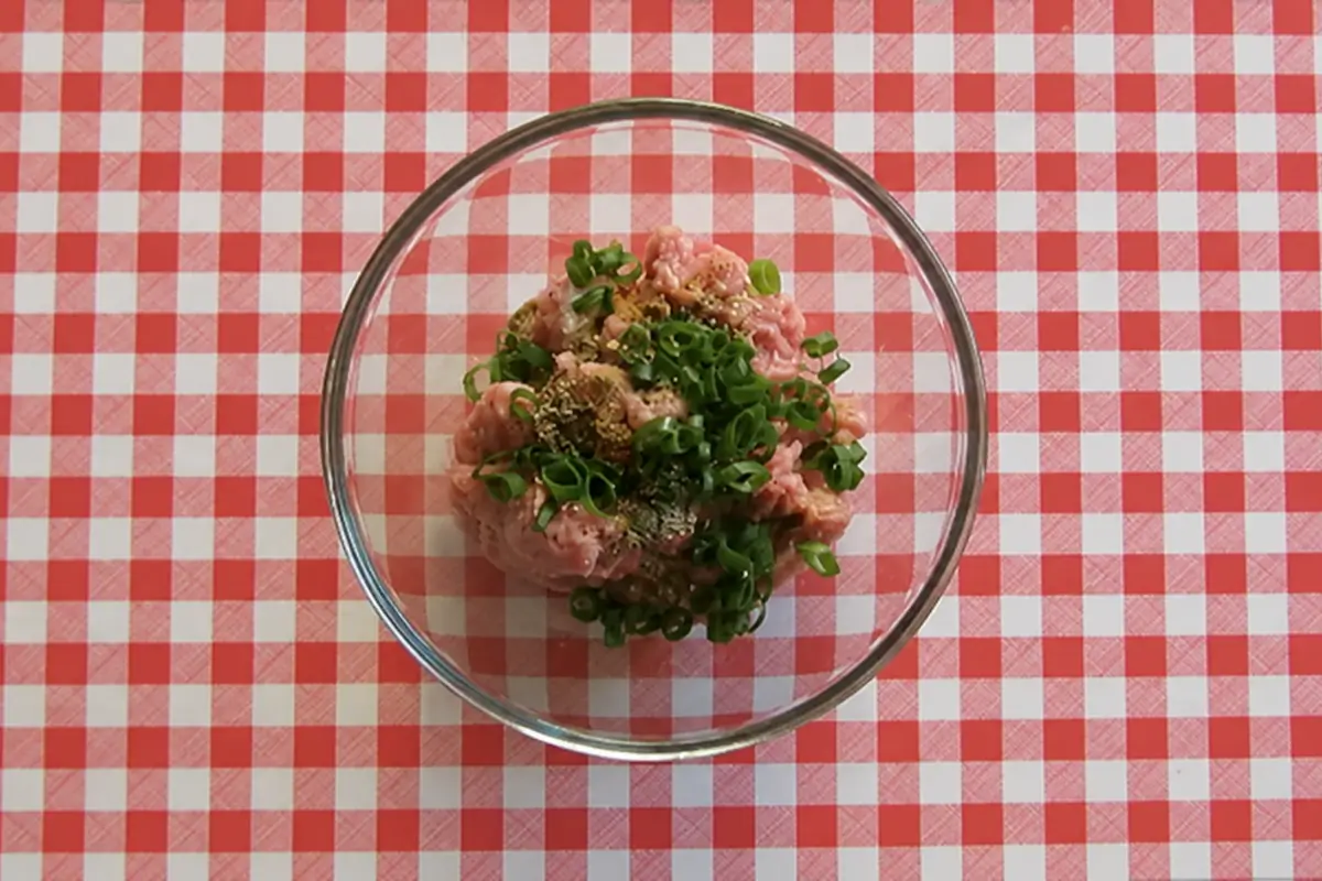 Pork mince with spring onion greens, oregano, cumin and paprika ready to be mixed.