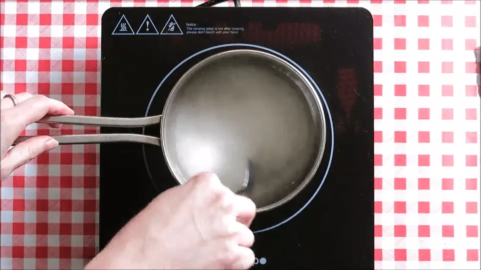 Water and sugar mixture heating in a saucepan to make syrup for Mulberry Granita.