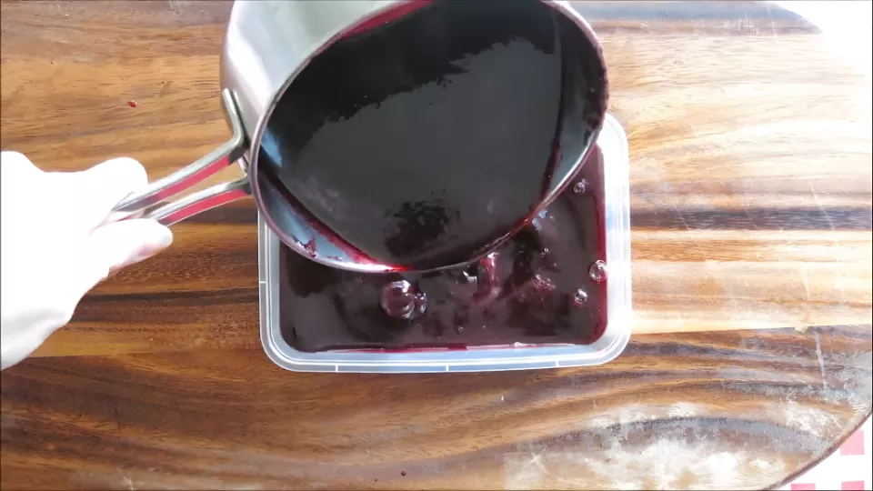 Pouring the mulberry syrup mixture into a container before freezing.
