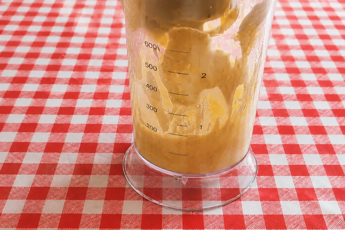 Homemade mustard mayo thickening inside a hand blender container.