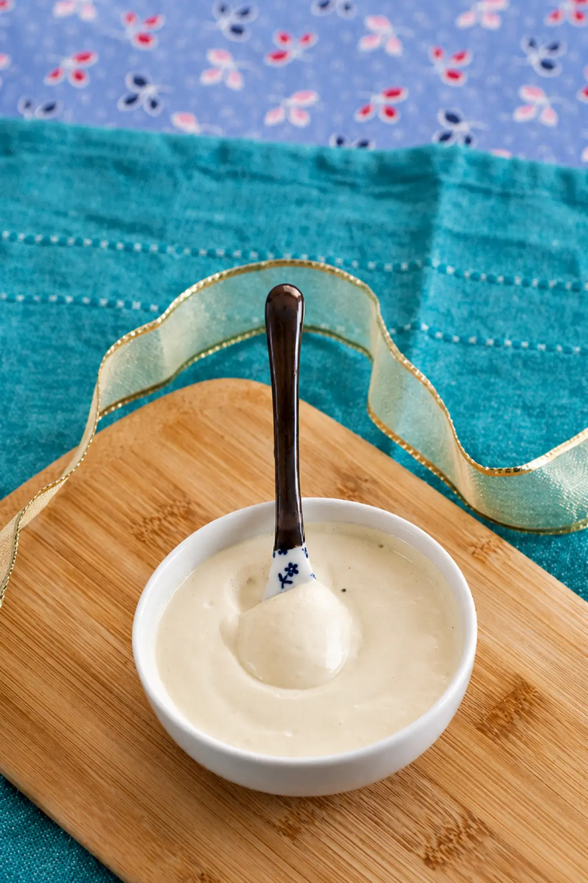 Smooth homemade mustard mayo served in a white bowl with a spoon.
