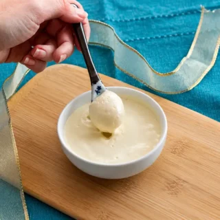 Spoon lifting silky homemade mustard mayo from a serving bowl.