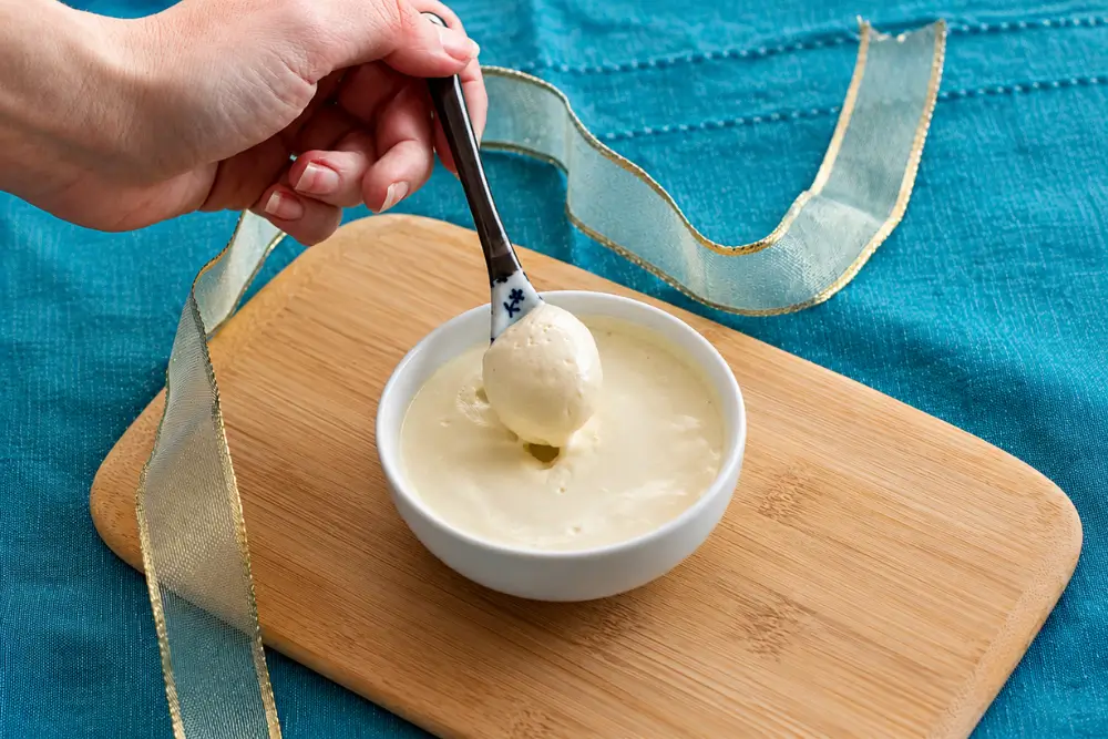Spoon lifting silky homemade mustard mayo from a serving bowl.
