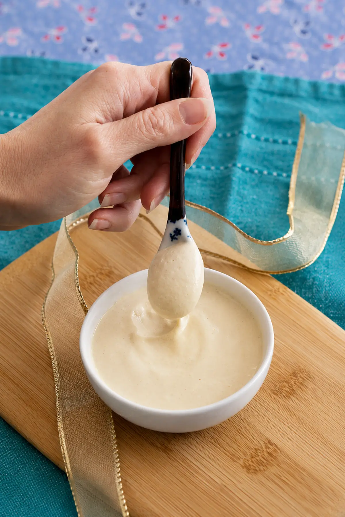 Spoon lifting creamy Low FODMAP mustard mayo from a small bowl.