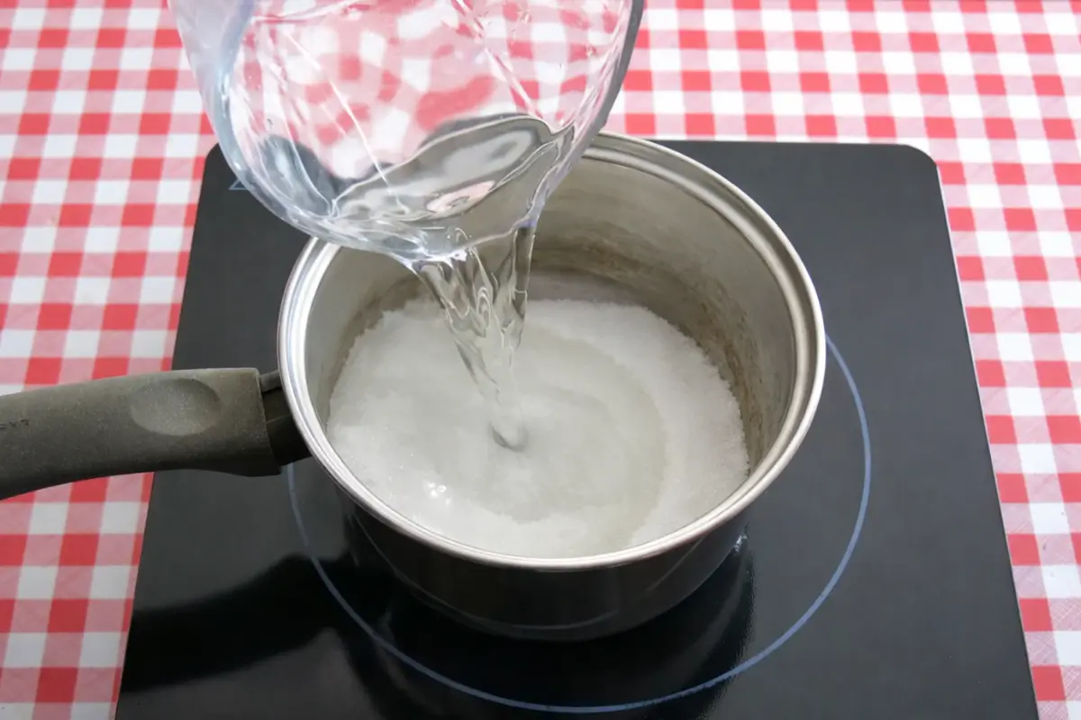 Water being poured into sugar in a pot to start the syrup.