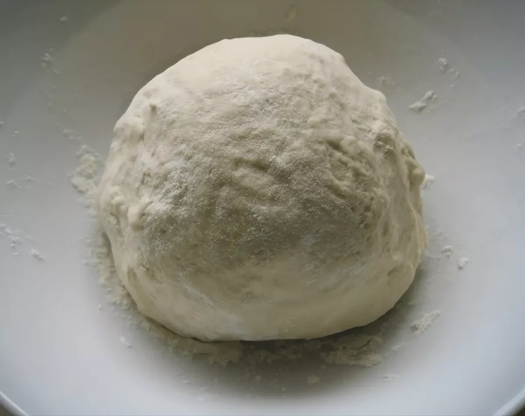 Homemade pizza dough shaped into a ball.