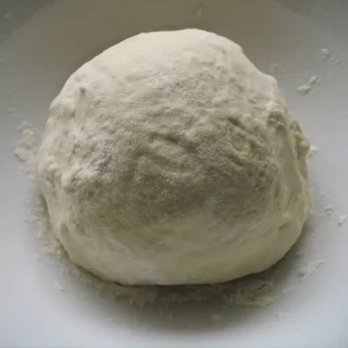 Homemade pizza dough after rising in a bowl.