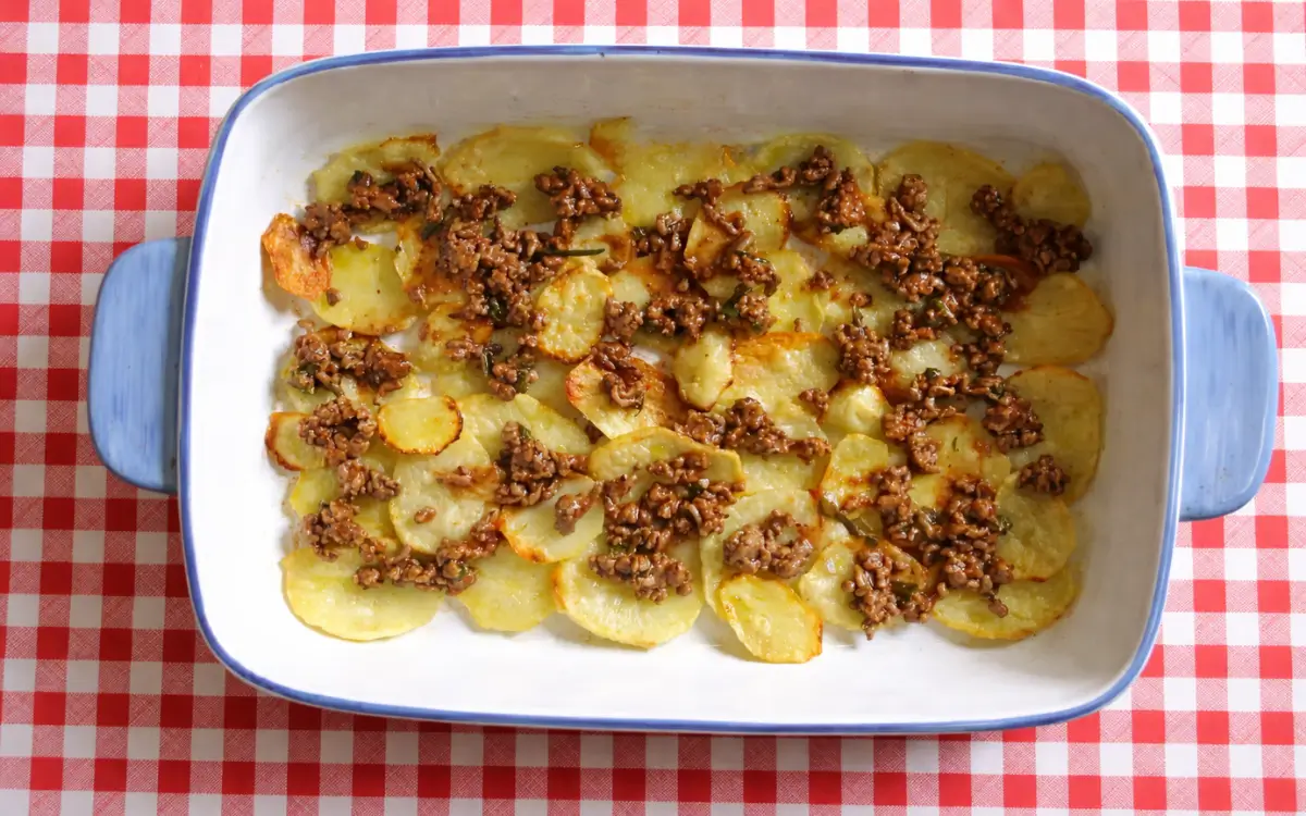 First layer of baked potato slices topped with spoonfuls of meat sauce.