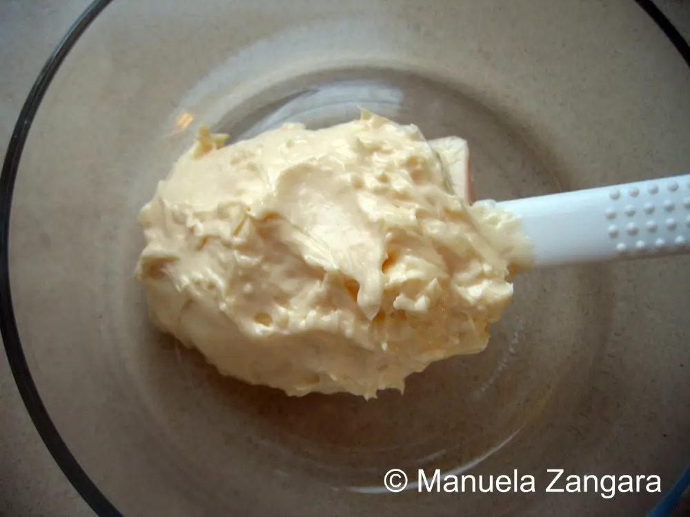 Thick homemade mayonnaise resting in a glass bowl with a spatula.