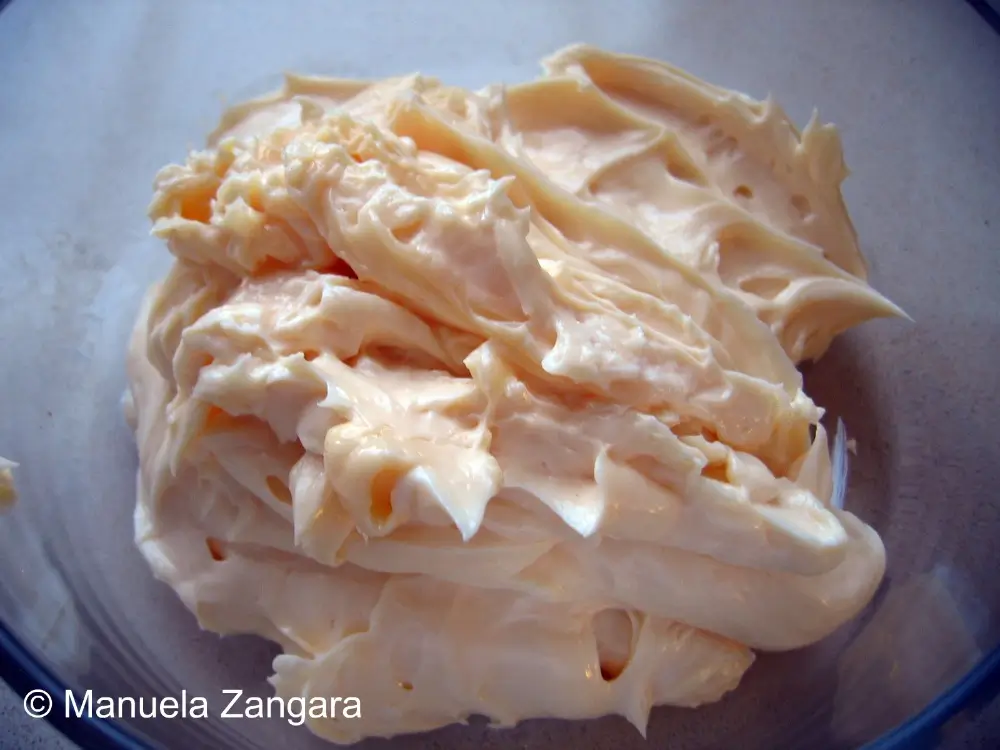 Close-up of thick, creamy homemade mayonnaise in a glass bowl.