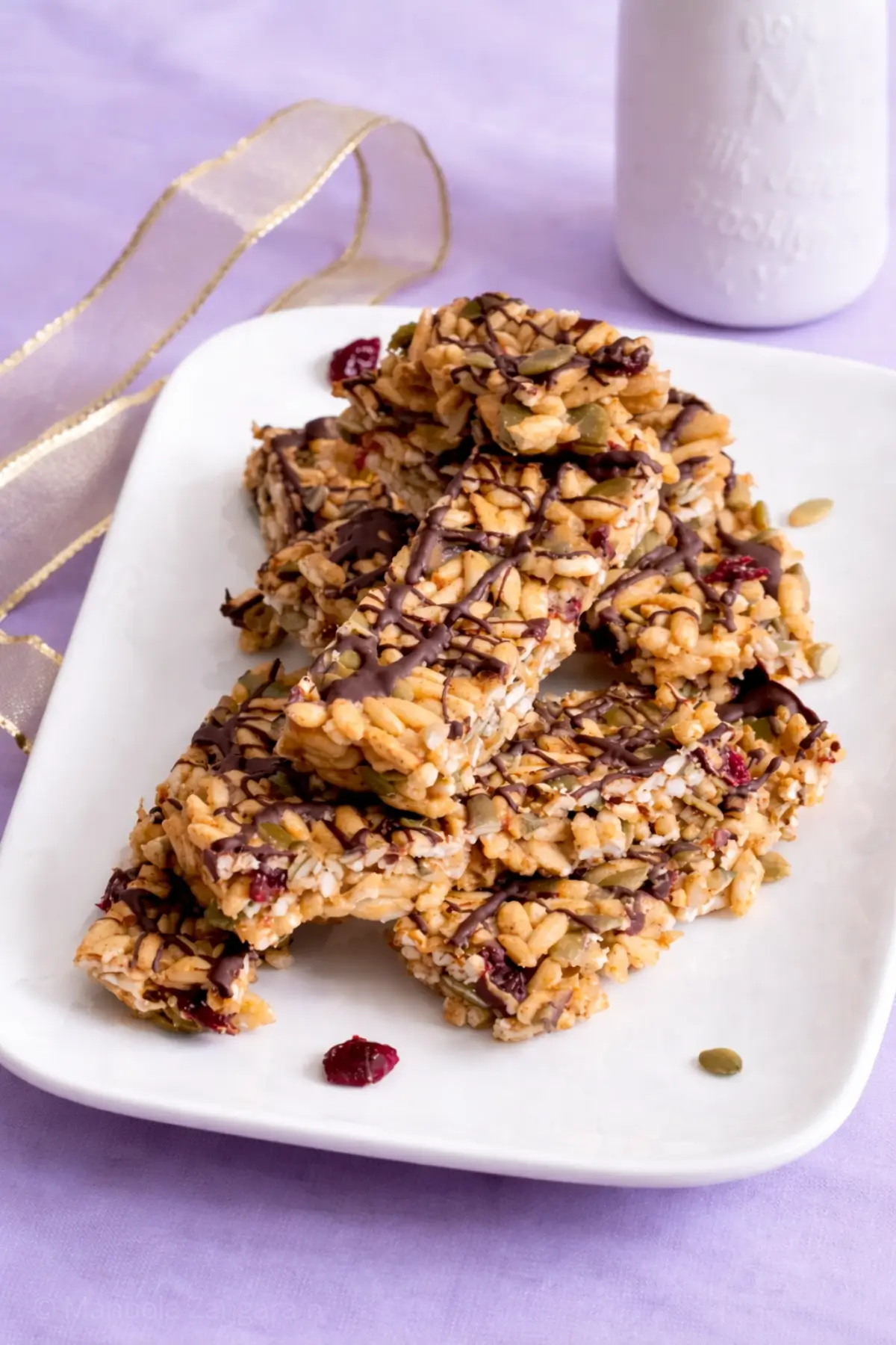 Stack of low fodmap protein bars with chocolate drizzle served on a white plate.