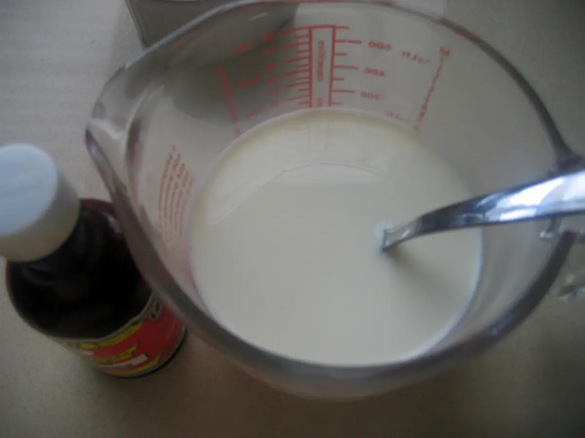 Milk mixed with vanilla extract in a measuring cup.