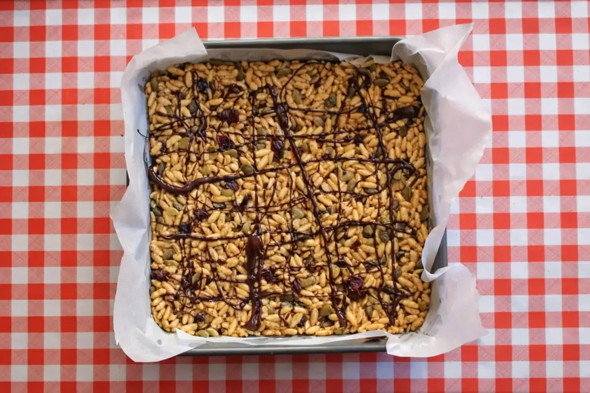 No-Bake Energy Bars drizzled with melted chocolate in a baking tray before chilling.