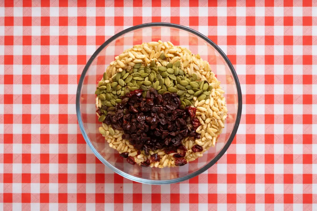 Bowl of ingredients for low fodmap snack bars with puffed rice, pepitas, and cranberries.