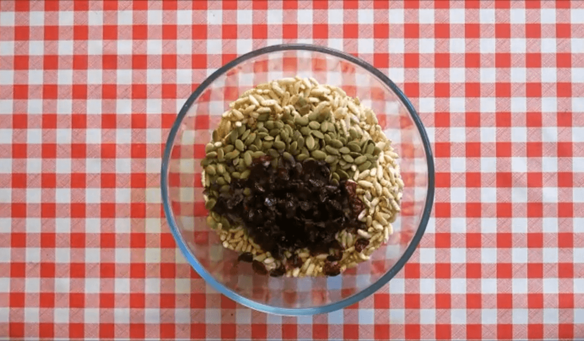Puffed rice, pepitas, and dried cranberries measured in a glass bowl.