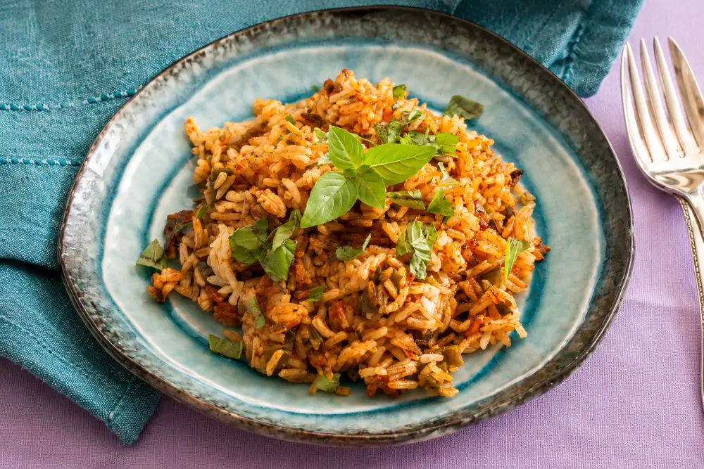 Savoury tomato rice served with fresh basil on top.