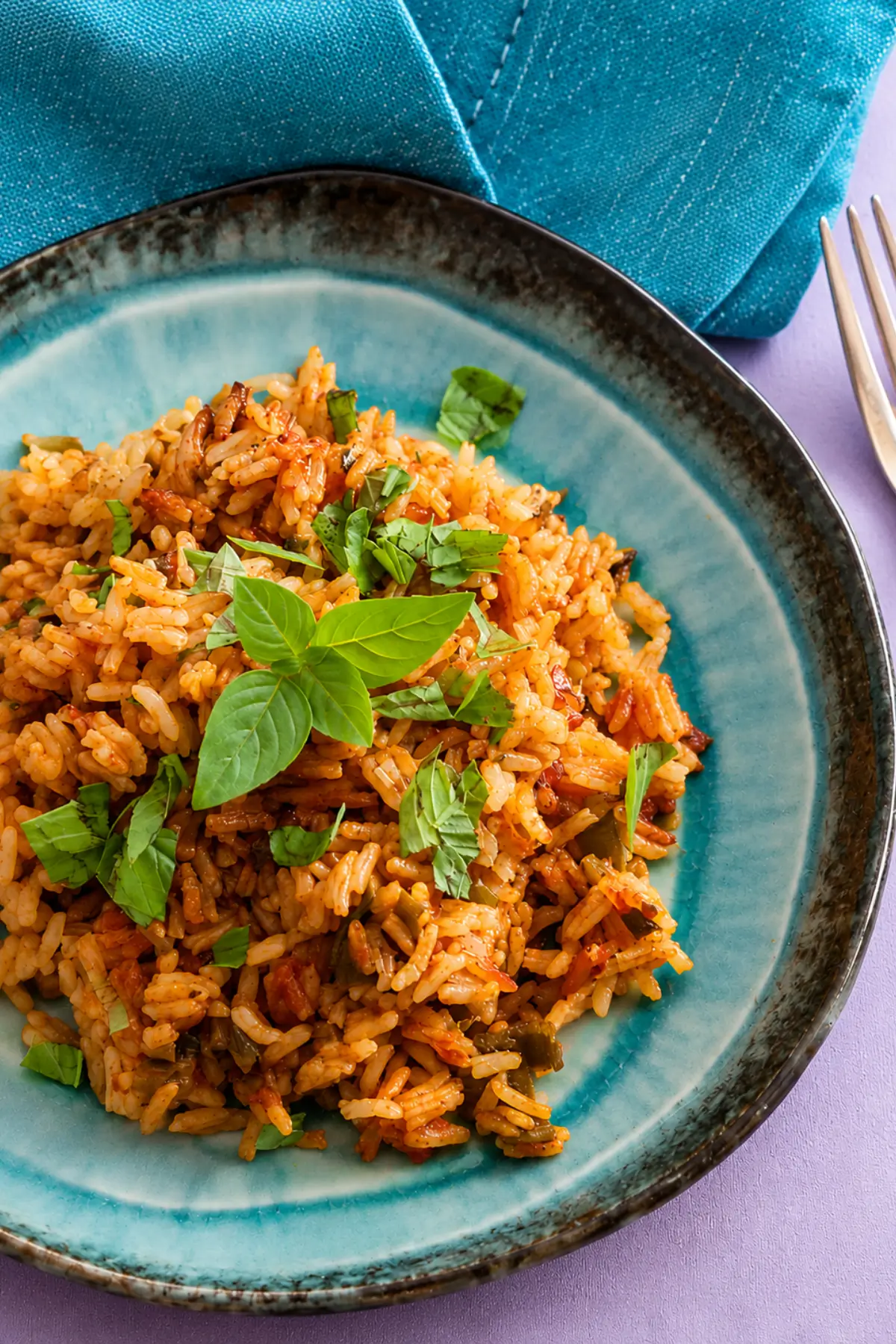Low FODMAP Tomato Basil Rice served on a blue plate with fresh basil.