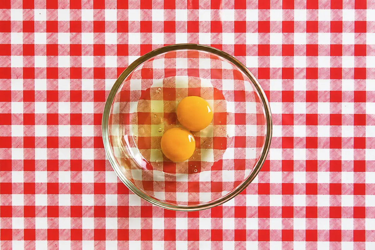 Two eggs in a glass mixing bowl.