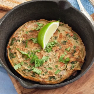 Low FODMAP Masala Omelette served in a cast iron pan with fresh coriander and lime.