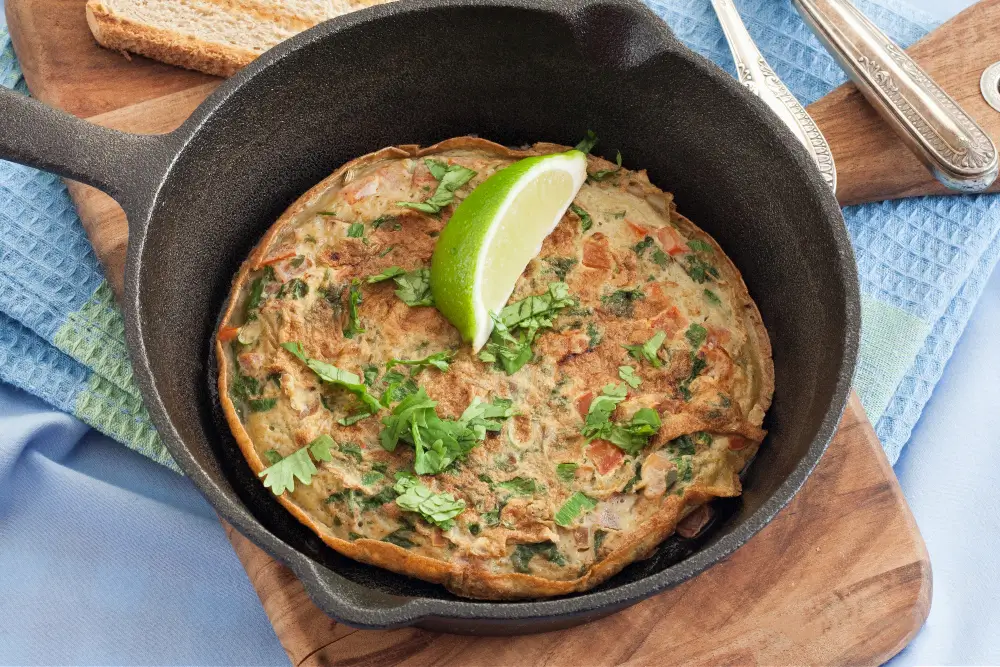 Low FODMAP Masala Omelette served in a cast iron pan with fresh coriander and lime.