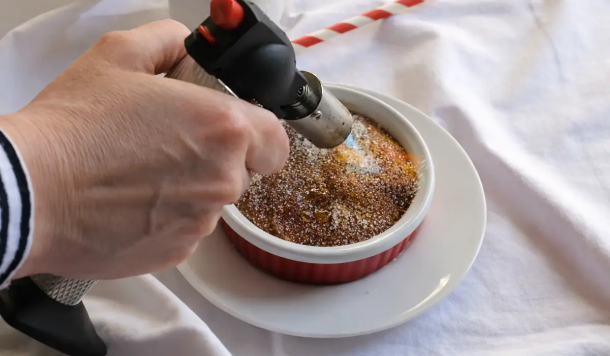 Using a kitchen torch to caramelise sugar on chilled custard.