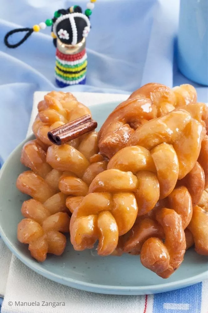 Traditional South African koeksisters with cinnamon stick and bead doll decor.
