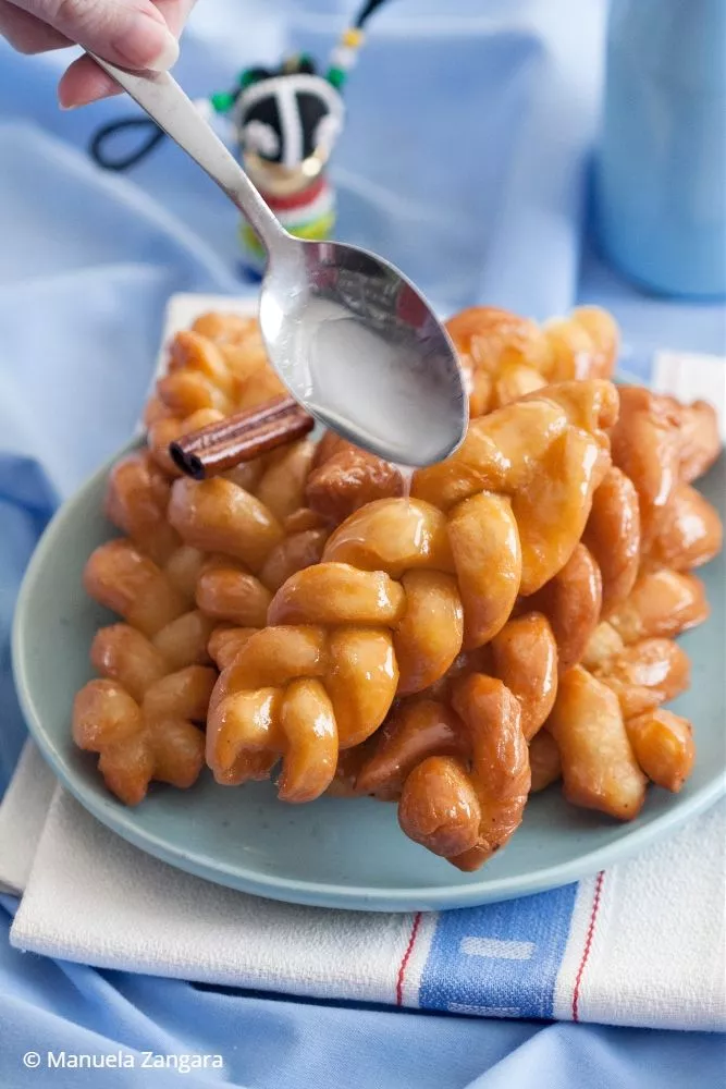 Spoon pouring syrup over freshly fried South African koeksisters.