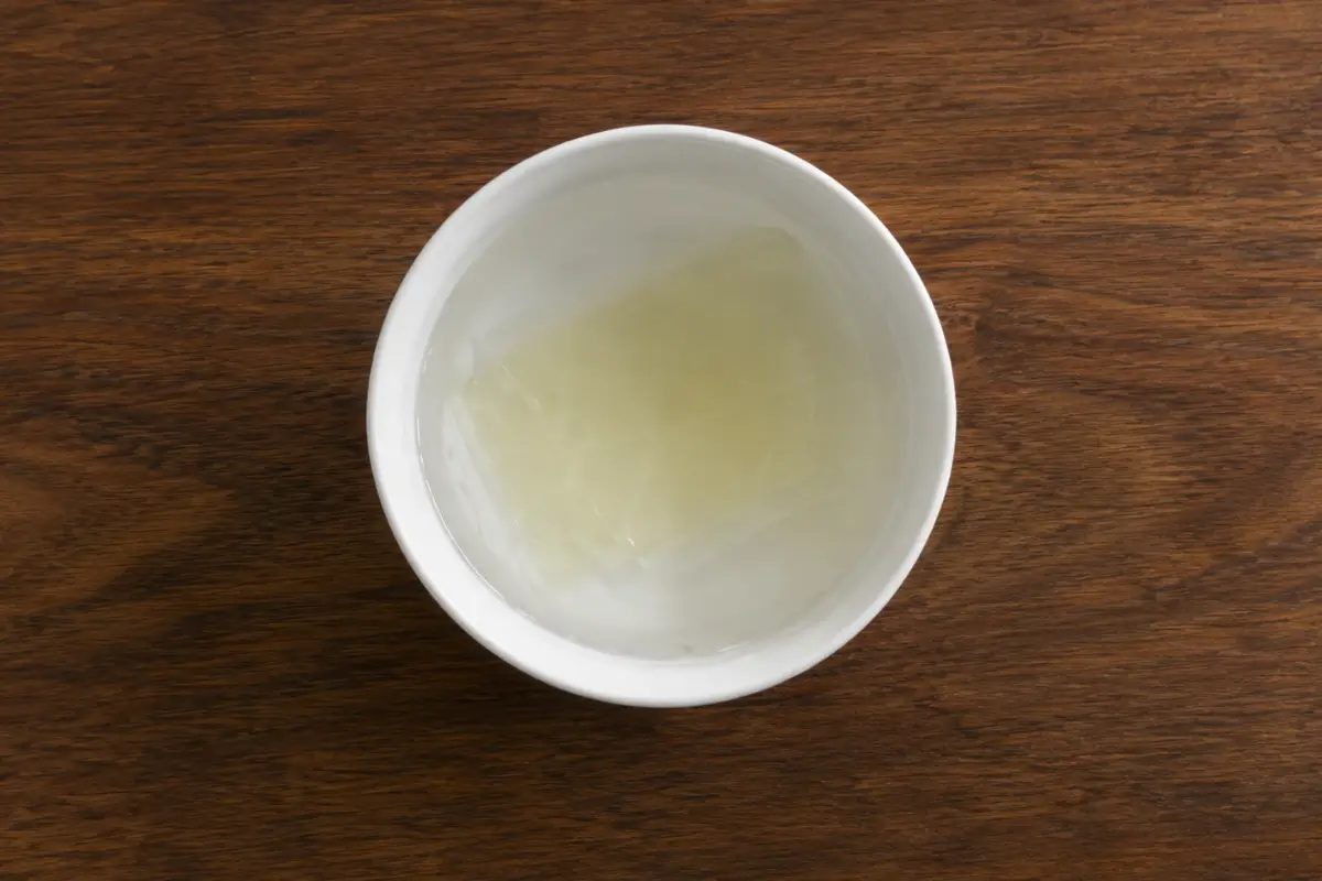 Gelatine sheets soaking in cold water inside a white bowl.