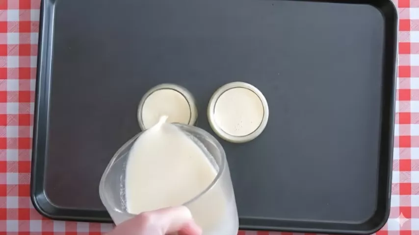 Pouring creamy Lemon Panna Cotta mixture into small glasses before chilling.