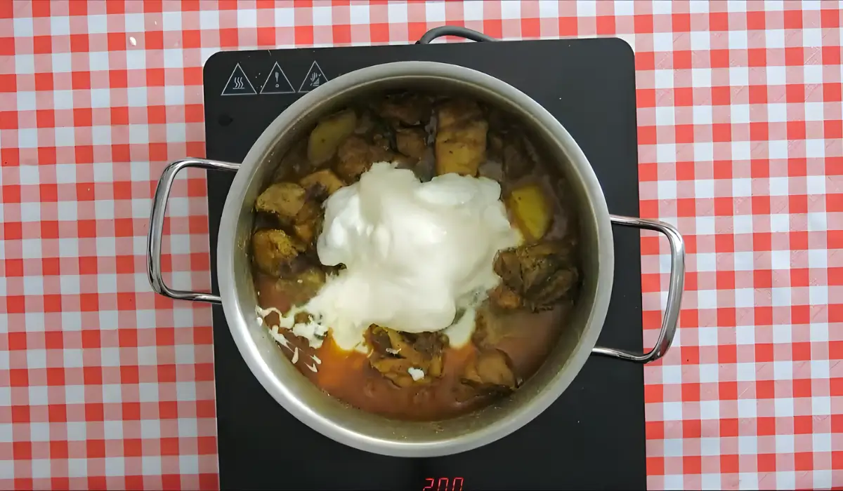 Lactose-free yoghurt added to chicken curry in a pot.